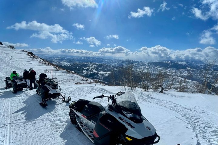 a group of people sitting on top of a snow covered slope